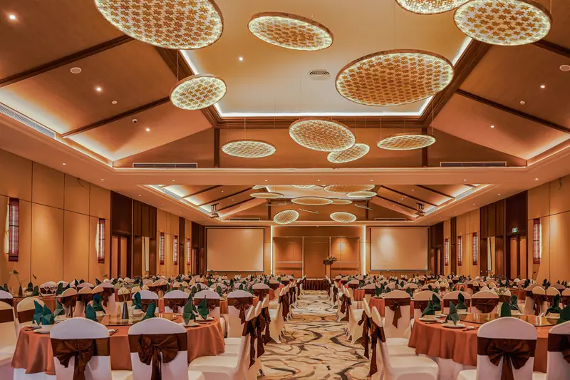 Grand Ballroom bày bàn tròn cho tiệc, trần gỗ có đèn tròn đan mây