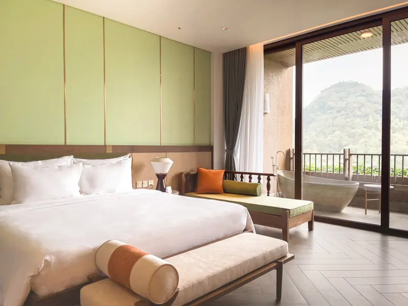 Phòng ngủ Family Suite giường đôi, ghế dài, cửa kính ra ban công có bồn tắm
